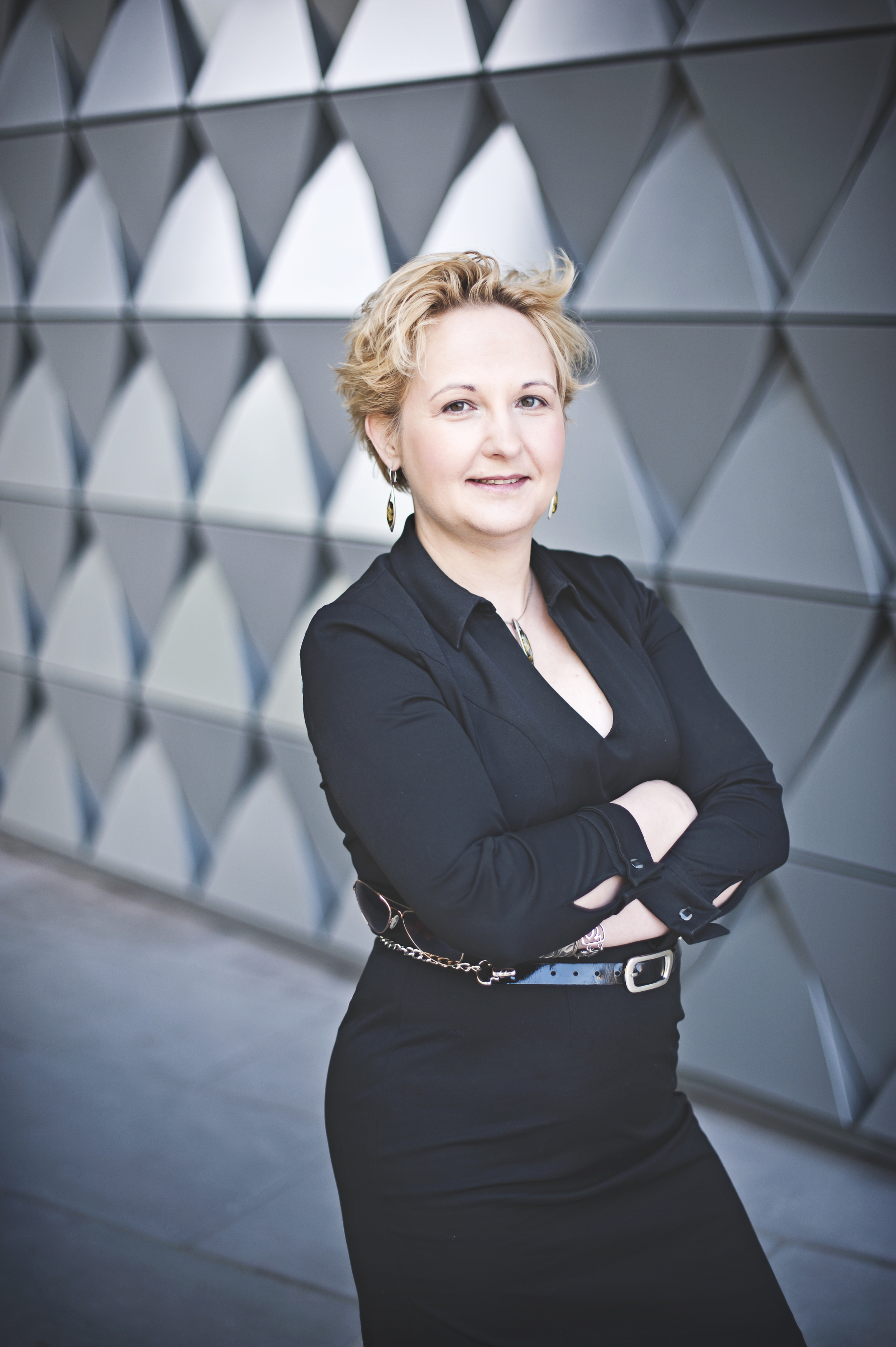 smiling woman with folded arms standing in front of a building