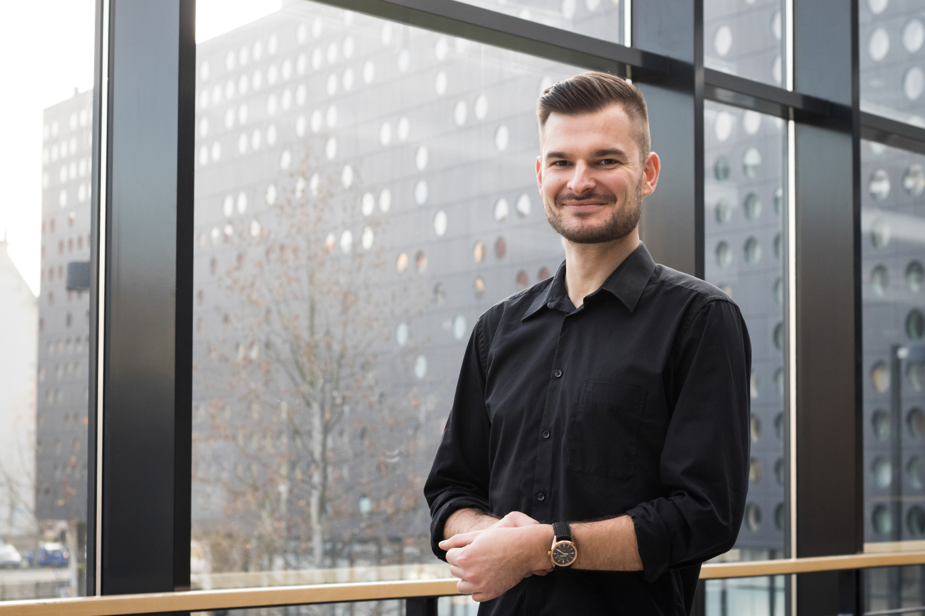 smiling man, short hair, black shirt, watch